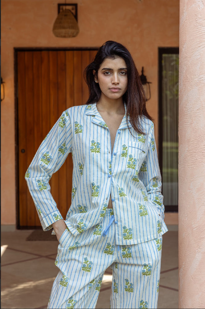 Woman wearing a light blue pajama set with floral patterns in front of a peach-colored wall.
