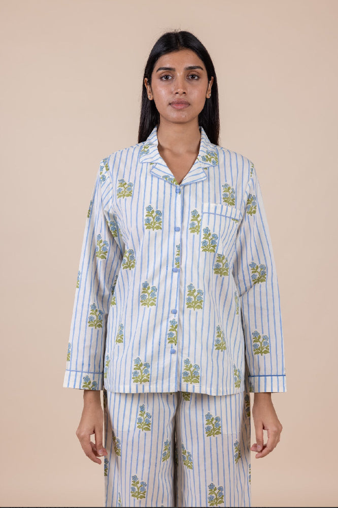 Woman wearing a light blue and white striped pajama set with floral patterns on a beige background