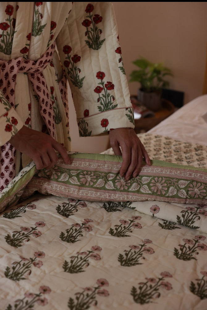 Model arranging floral-patterned quilt condicote poppy on a bed