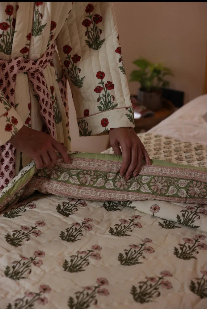 Model arranging floral-patterned quilt condicote poppy on a bed