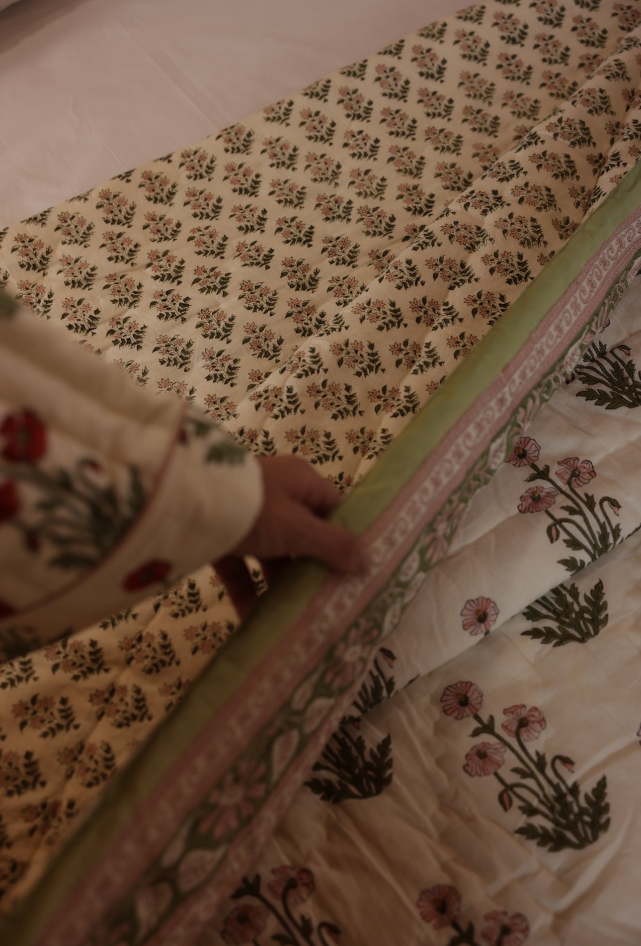 Models hands turning back condicote poppy quilt to show reverse side
