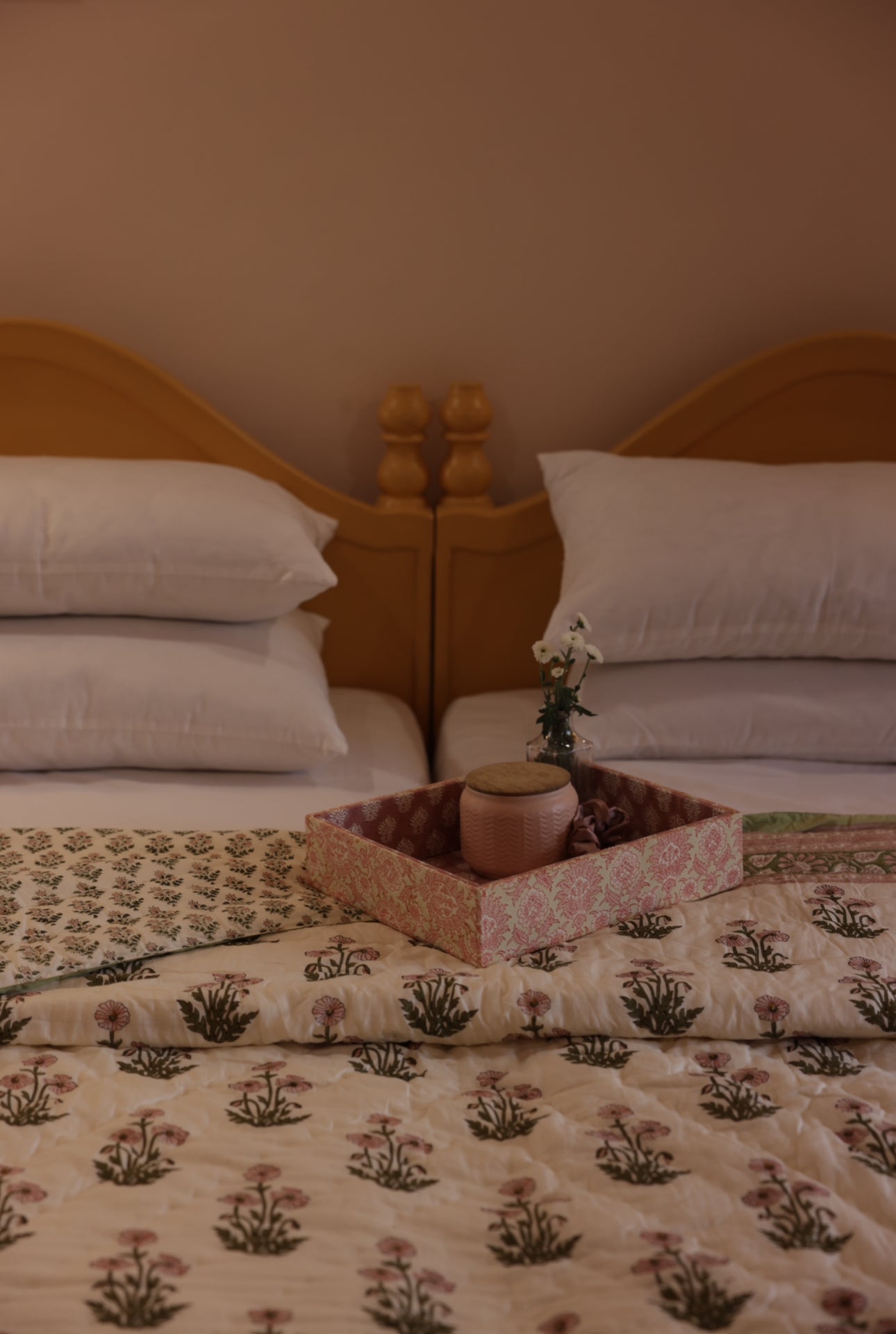 Condicote Poppy quilt laid on a bed with a fabric tray and candle