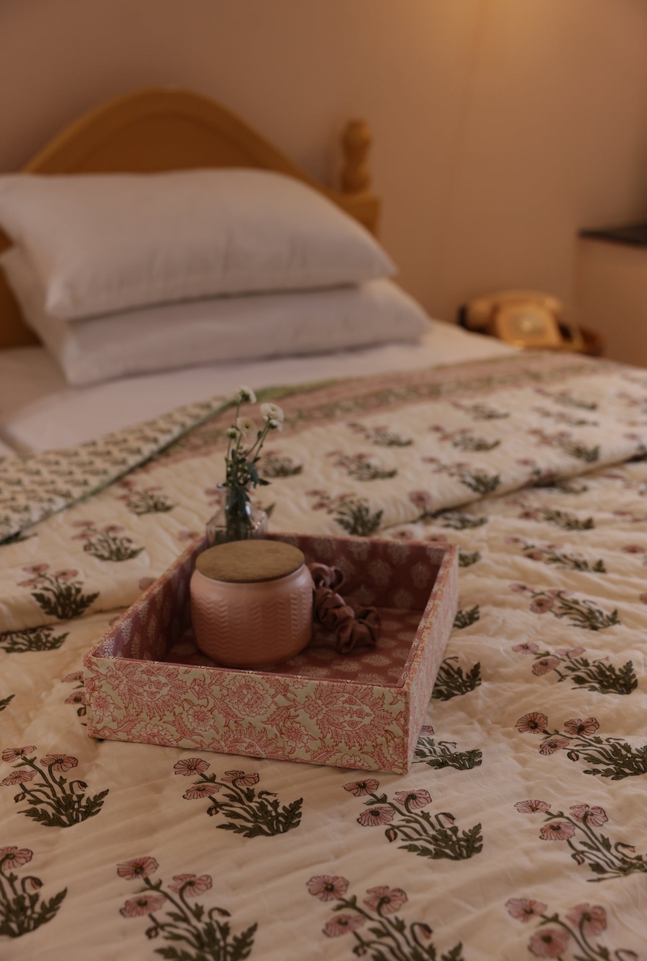 Condicote Poppy quilt laid on a bed with fabric tray