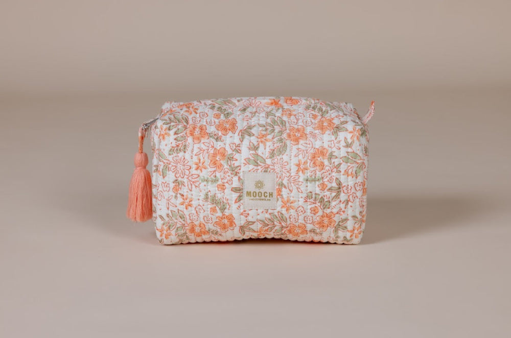 Floral patterned cosmetic bag with a tassel on a beige background