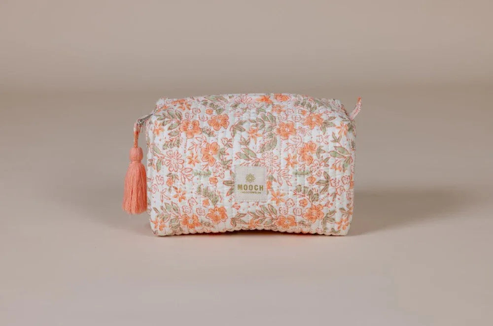 Floral patterned cosmetic bag with a tassel on a beige background