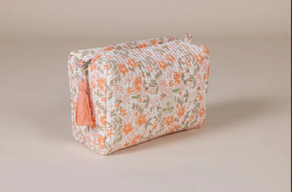 Floral patterned toiletry bag with a tassel on a beige background