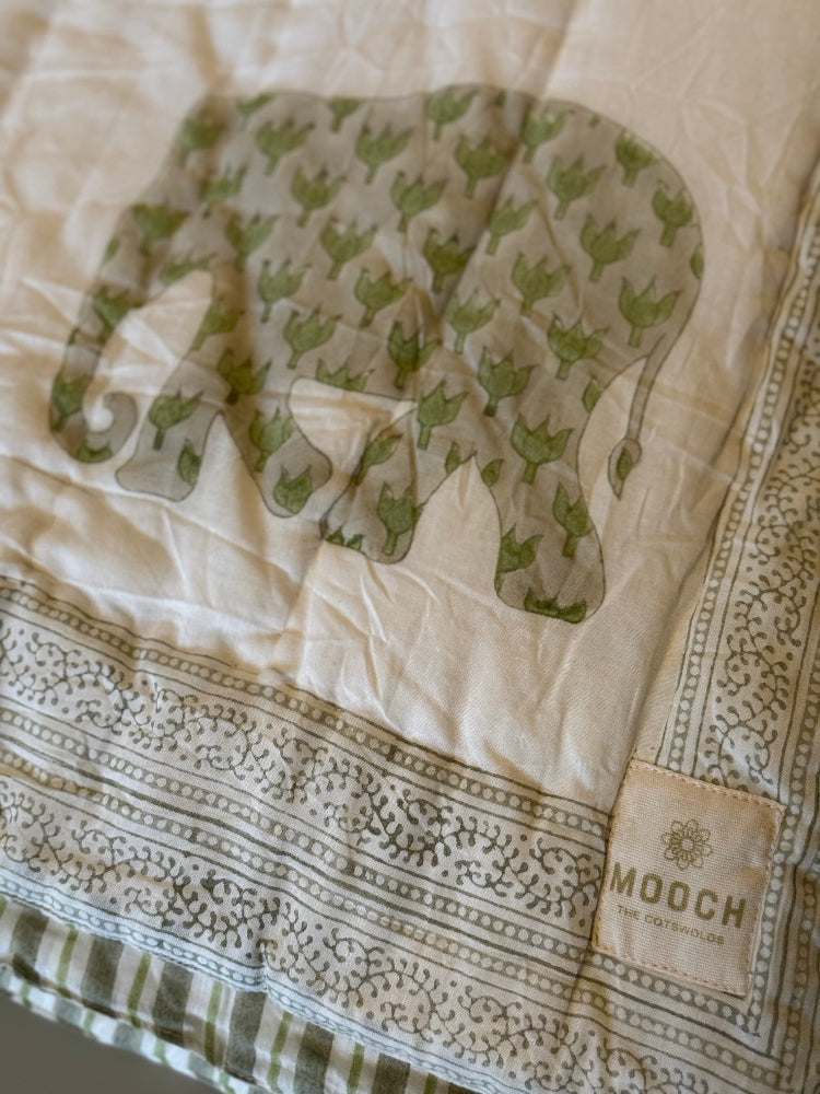 Enzo quilt with green elephant design and 'Mooch' label on a beige background