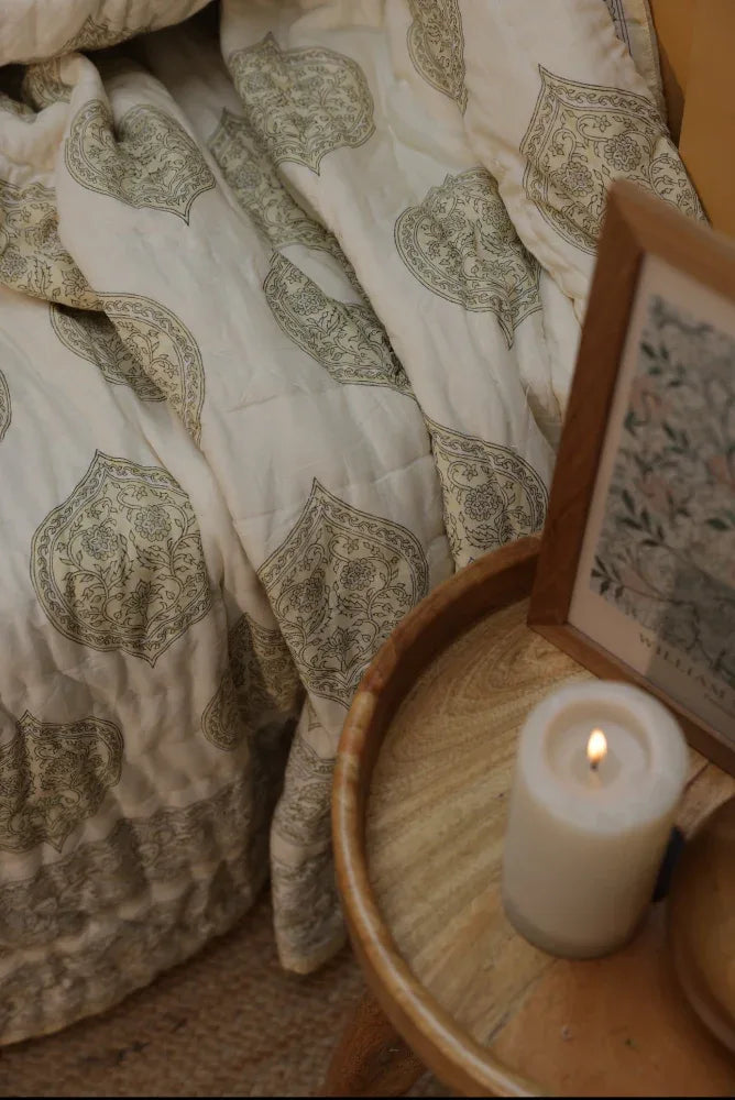 Candle on a wooden side table next to kiftsgate stone bedding