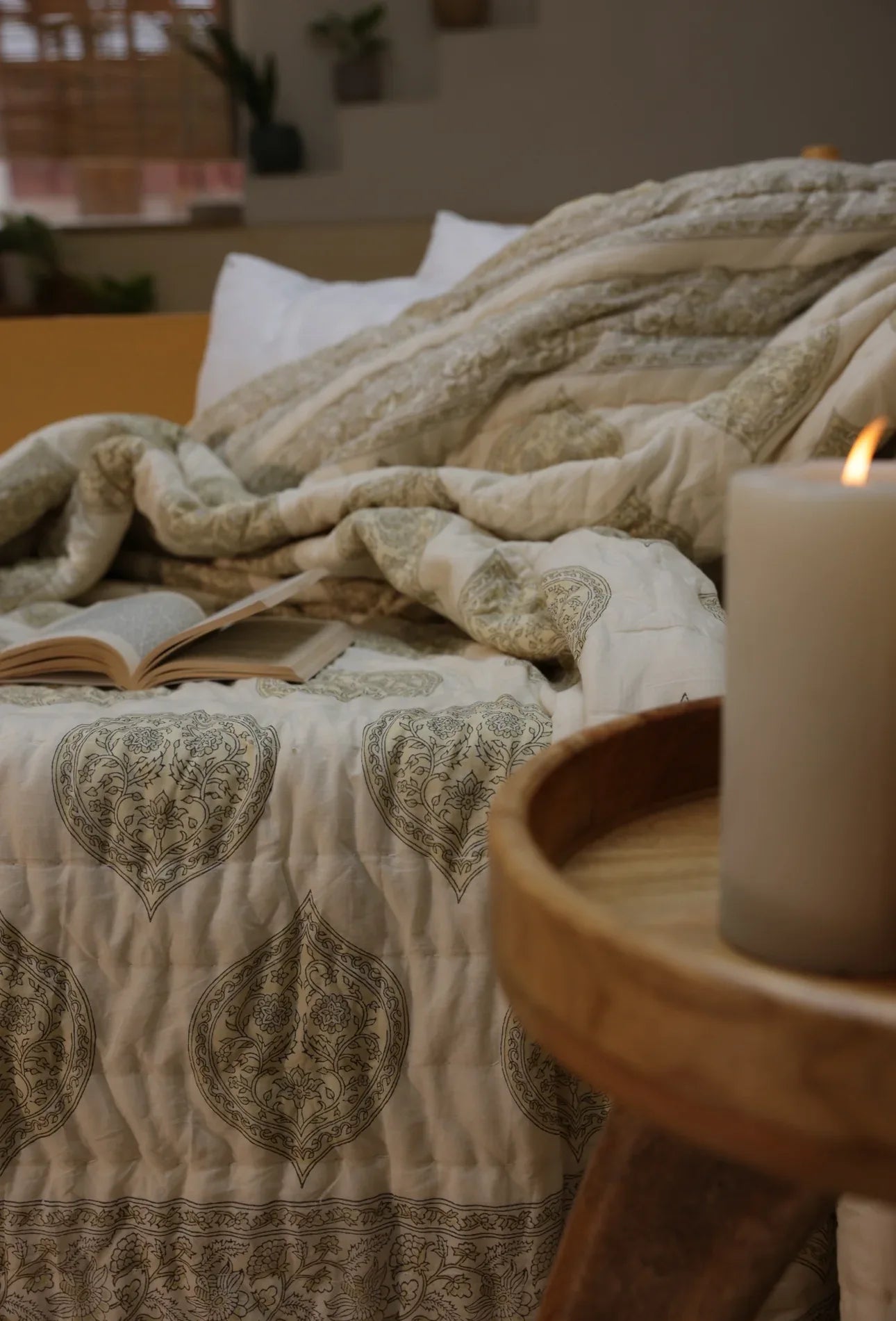 Kiftsgate stone quilt with open book and candle burning next to bed