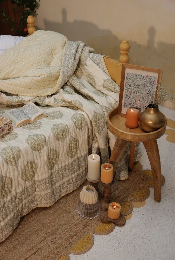 Bedroom with a kiftsgate stone quilt, candles, and a small table.