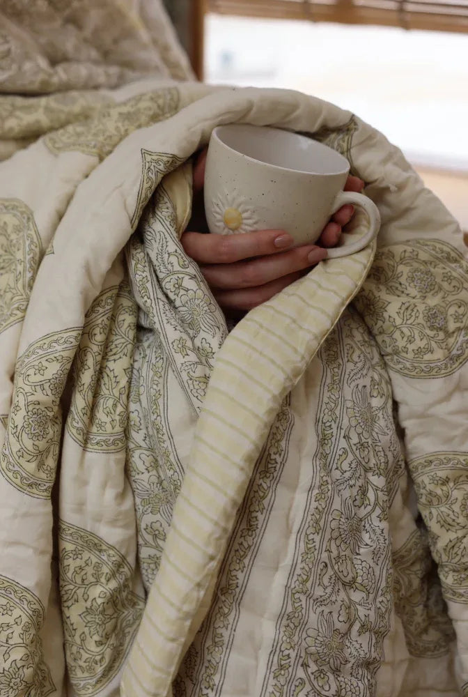 Kiftsgate stone quilt wrapped around a model holding a cup of coffee