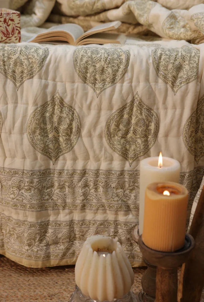 Kiftsgate stone quilt on a bed with a book and candles