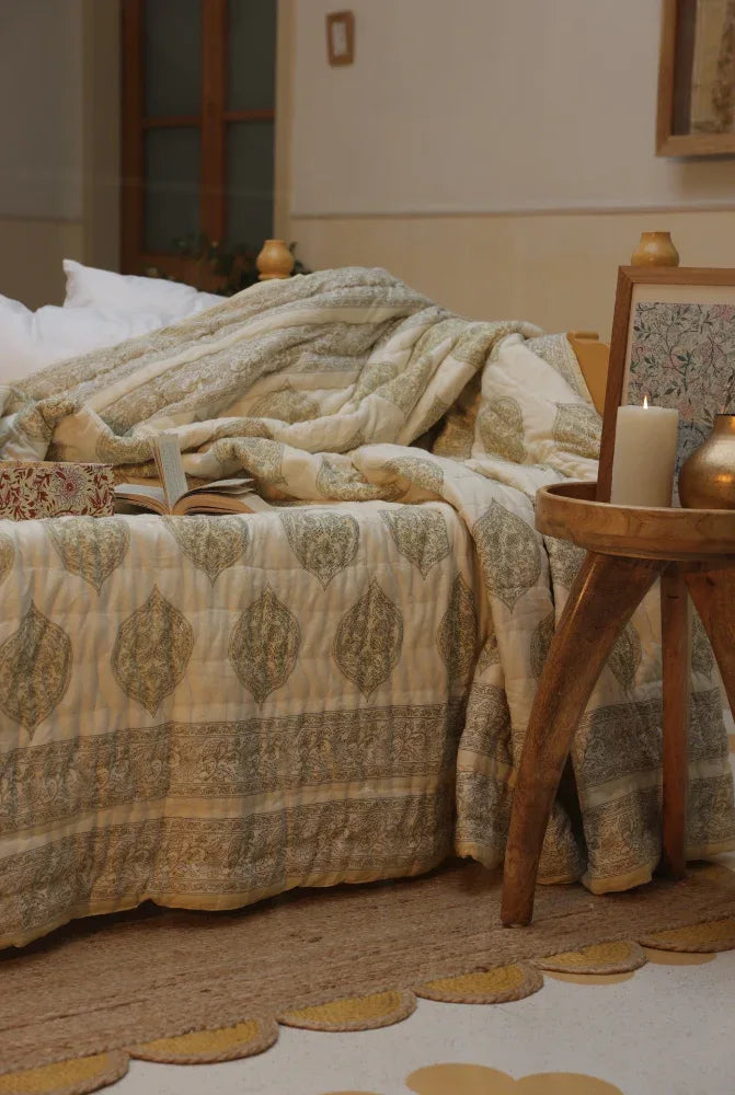 Bedroom with a bed covered in kiftsgate stone quilt and a wooden side table