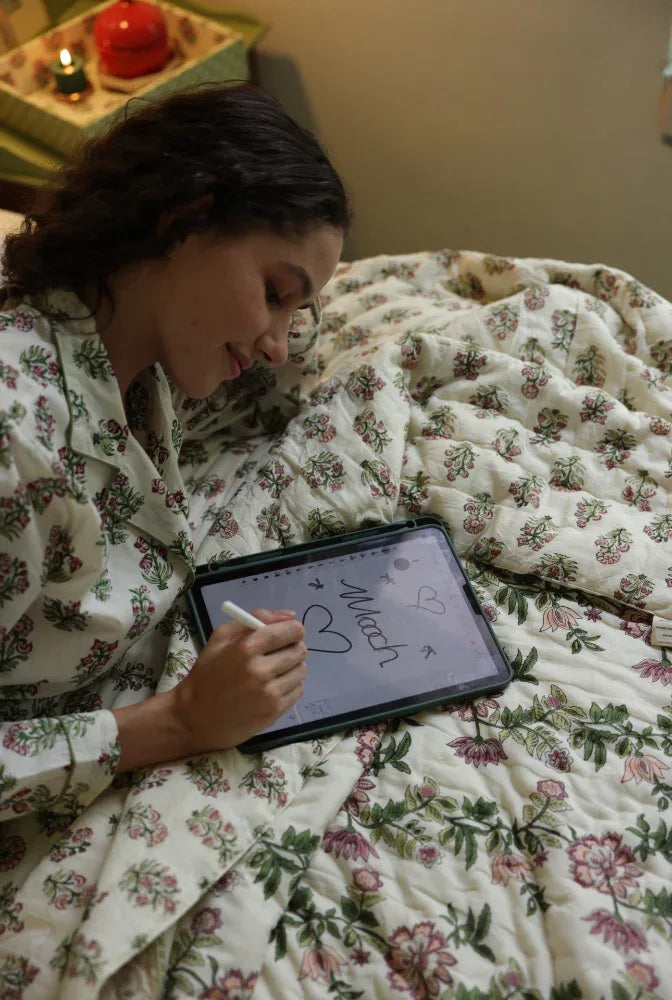 Model lying down on paxford willow quilt doodling on a tablet