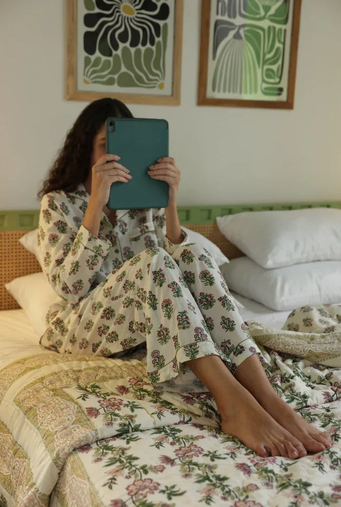 Model sat on Paxford Willow quilt hiding her face behind a tablet
