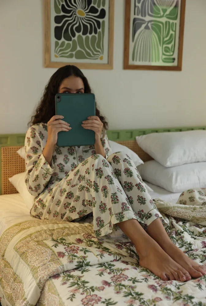 Model sitting on paxford willow quilt hiding her face with a tablet