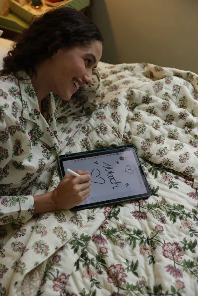 Model lying on paxford willow quilt laughing with tablet