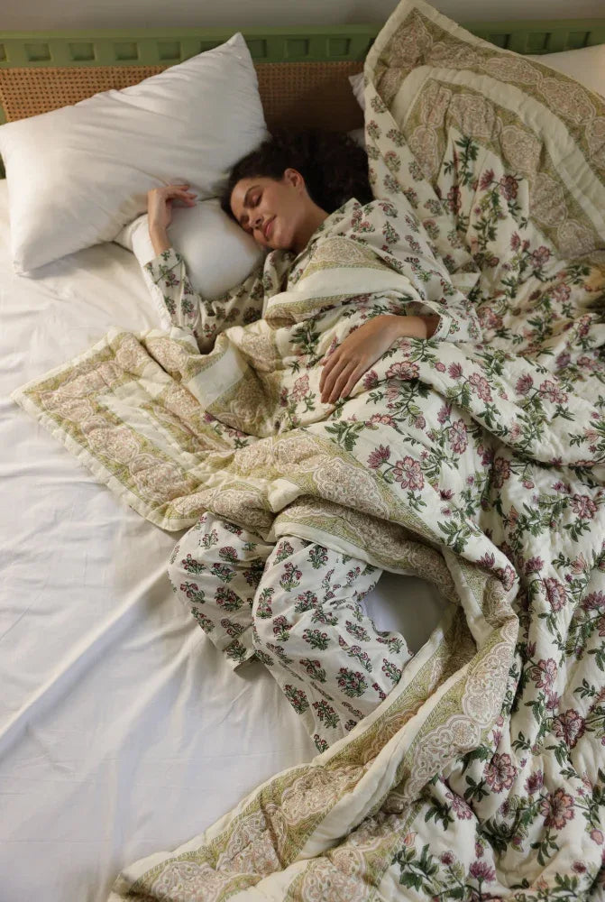 Woman lying in bed under a floral quilt
