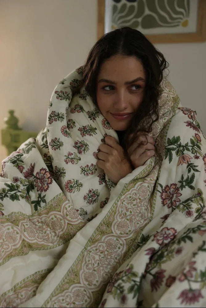 Woman wrapped in a floral-patterned quilt indoors