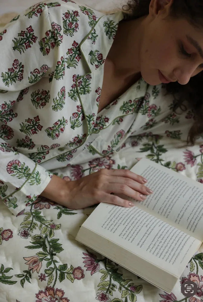 Model in floral whisper pyjamas reading a book laid on paxford willow quilt