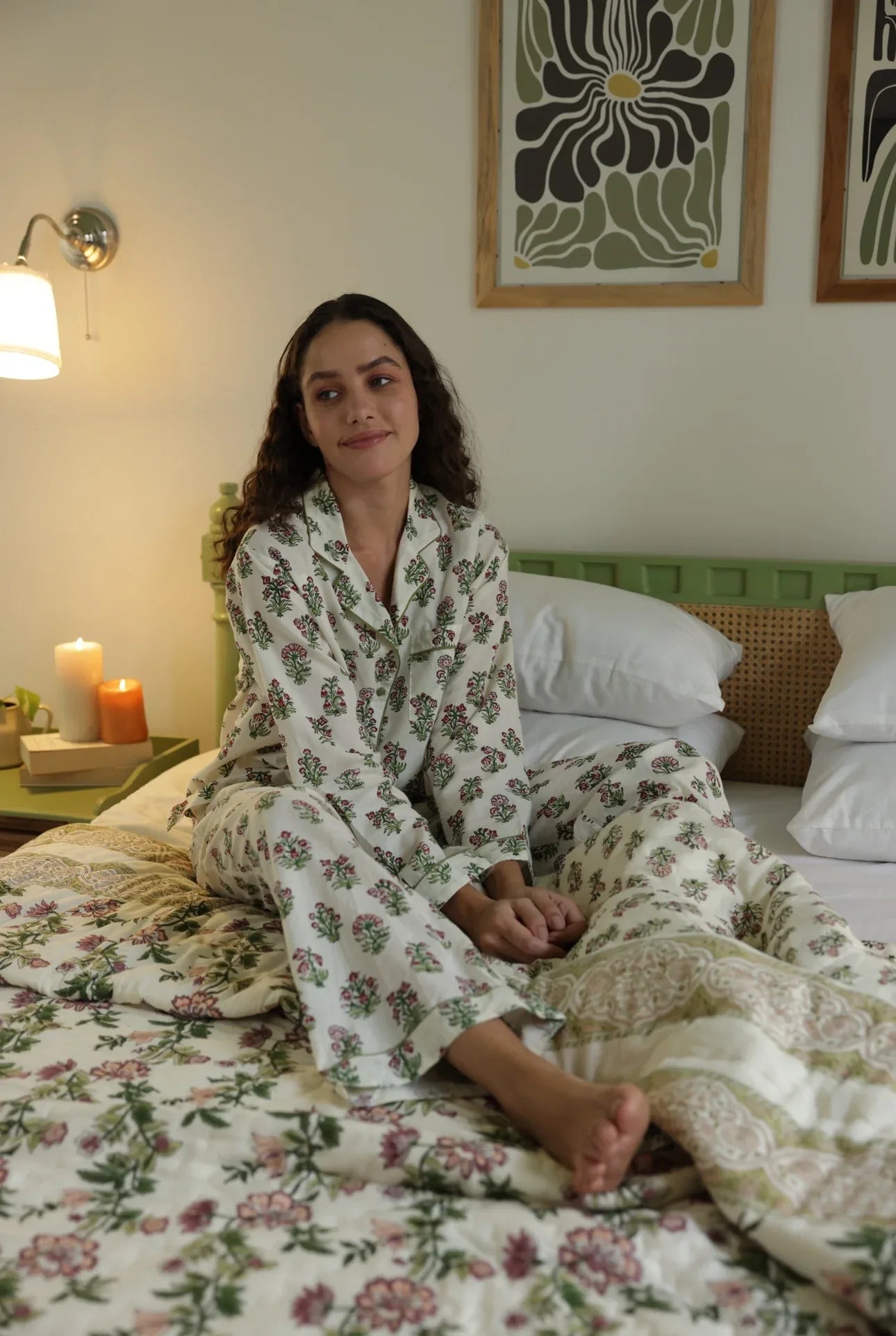 Model sat in floral whisper pyjamas glancing at the room while sat on paxford willow quilt