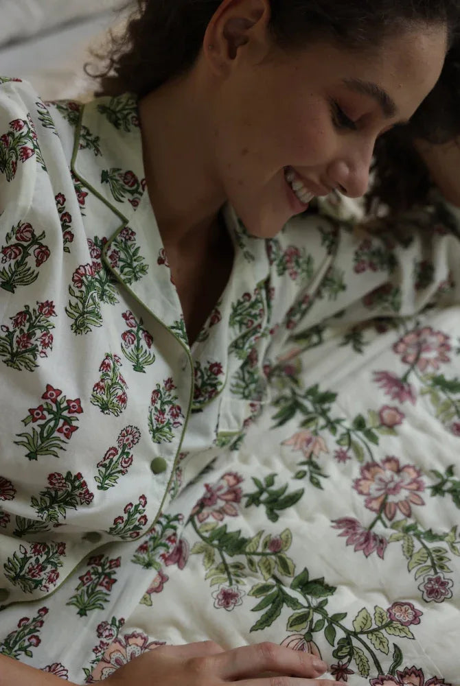 Model wearing floral whisper pyjamas laid on Paxford Willow quilt