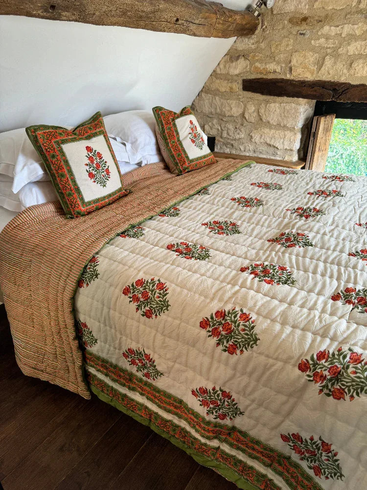 Bed with Wilson amber quilt and cushions in a cotswold stone bedroom setting.
