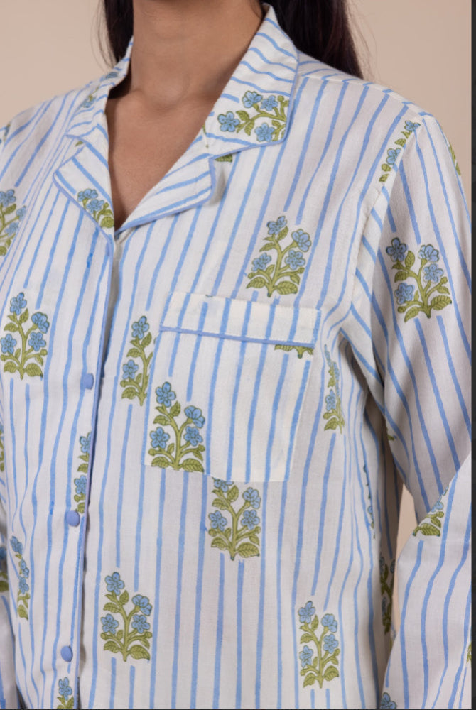 White pyjama shirt with blue stripes and floral patterns worn by a person