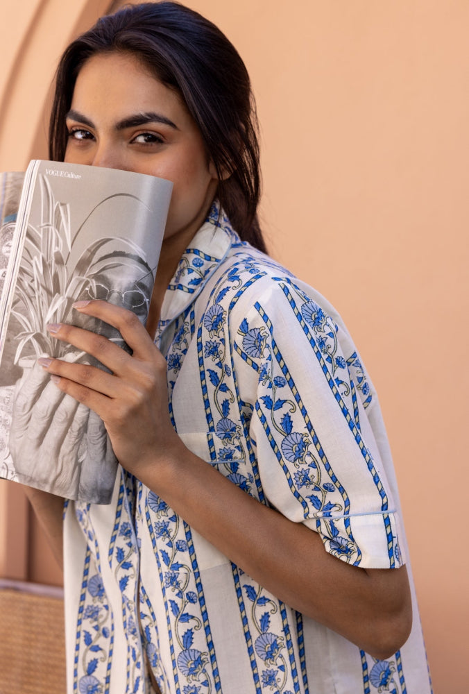 Model wearing Cobalt Ribbon Cotton Pyjamas, with her face behind a magazine