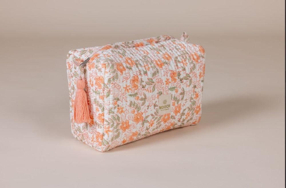 Floral patterned toiletry bag with a tassel on a beige background