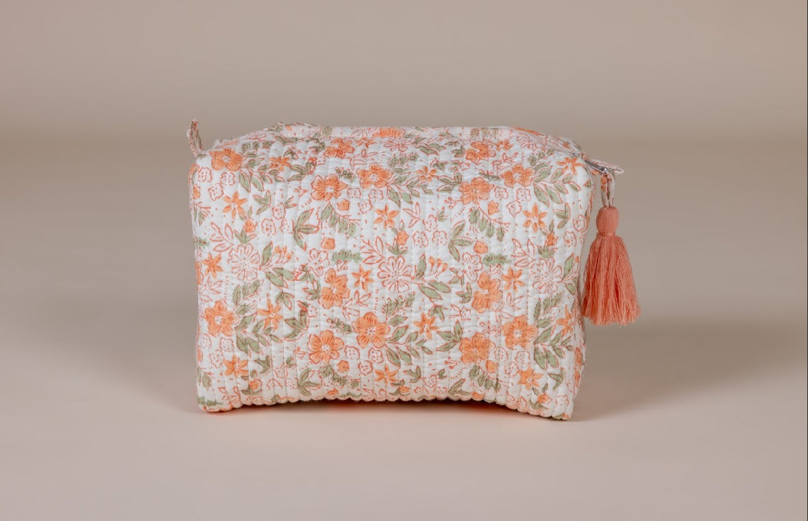 Floral-patterned wash bag with a tassel on a beige background