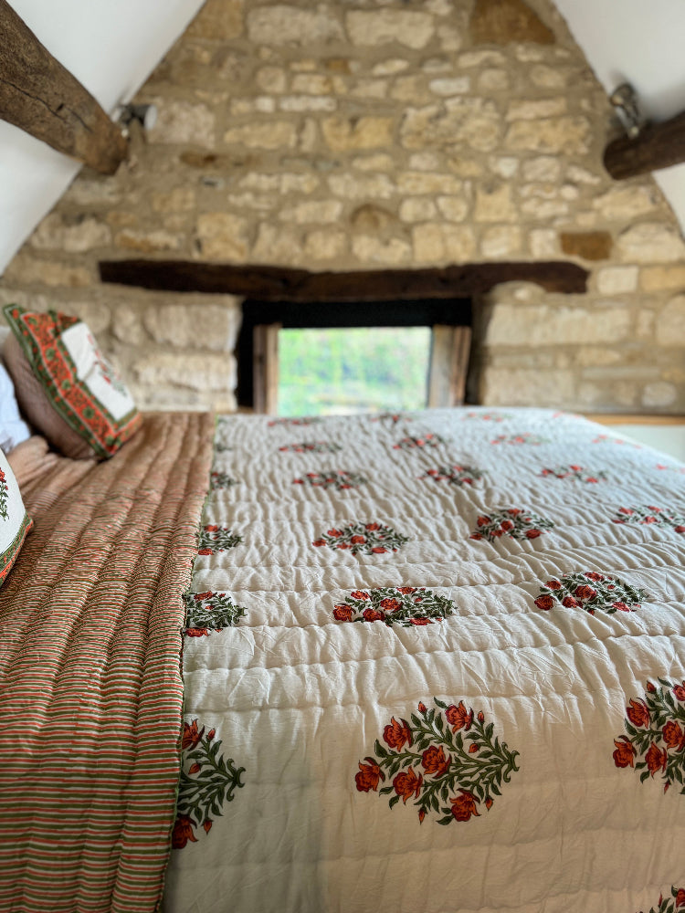 Bed with Wilson amber quilt in a rustic room with stone wall and wooden beams